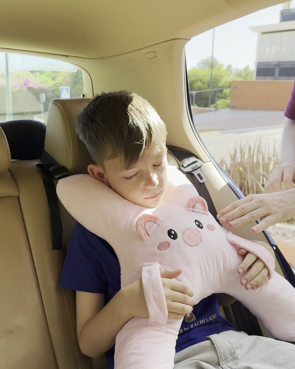 Niño dormido en el coche con la cabeza apoyada en el cojín Sleepy Piggy